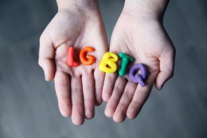 hands holding rainbow LGBTQ letters