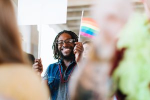 smiling man waving a rainbow flag
