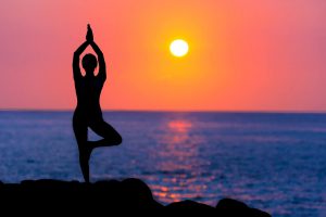 figure doing yoga near sunset and ocean