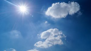Blue sky with couple of white clouds and bright sun.