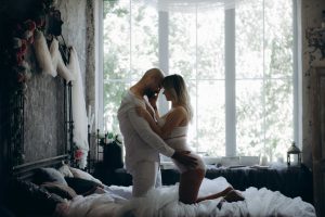 Woman and a man on their knees on a bed holdig each other.