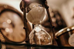 sepia colored photo of an hour glass with sand spilling down.