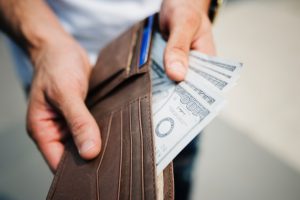 caucasian male hands pulling hundred dollar bills out of a wallet.