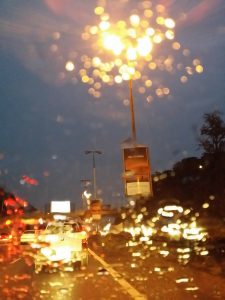 blurred vision out of a car's windshield into the night with lights.