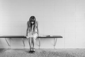 black and white picture of a young girl sitting on a bench looking down.