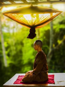monk meditating underneath a lamp