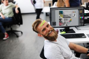 smiling worker in an office with a be happy sign
