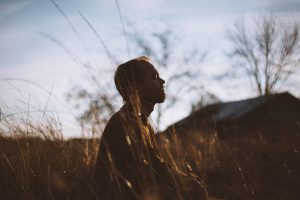 person meditating in a wheat field
