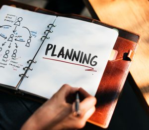 notebook opened up with the word "planning" written on the page.