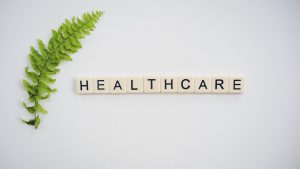 the word healthcare in scrabble letterswith a green leaf to the left side of it.
