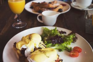 eggs benedict on a plate with some leafy greens.