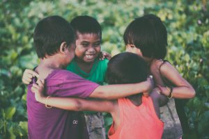 Four kids hugging each other in a circle.