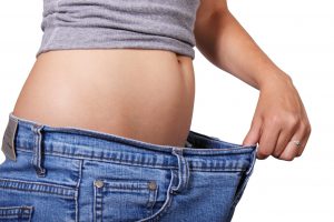 caucasian woman holding stretching out jeans from her waist.