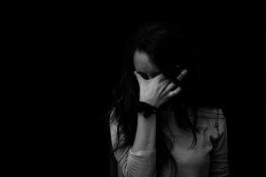 Black and white picture of caucasian woman holding her forehead with her hand.