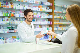 Caucasian man dressed in a white coat handing out medicine to someone.