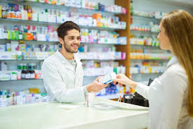 Caucasian man dressed in a white coat handing out medicine to someone.