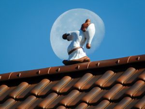 figure of a man whith sleeping cap on sleepwalking on the roof.
