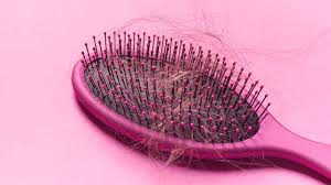 Pink brush with clumps of hair in it. 