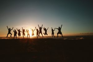 adults jumping on a beach after volunteering