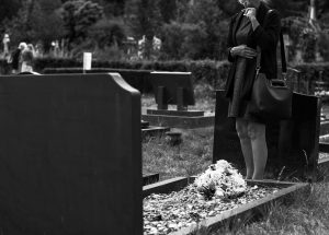 black and white funeral photo with grave and flowers