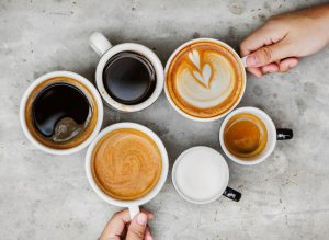 Different cups of coffee with cream in it or black.