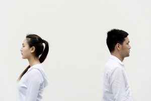 An asian woman and man with their backs towards each other.