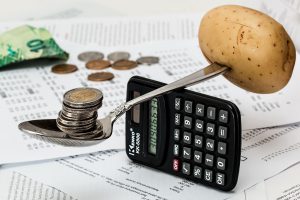 calculator balancinf a spoon with coins in it and a potato stuck on the other end.