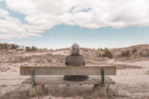 Woman with gray hair sitting on a bench looking out into the dessert.