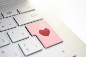 Keyboard buttons with one pink one with a red heart int he middle of it.