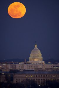 government building at night with an orange moon