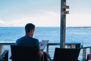 business owner reading a book by the ocean on a porch