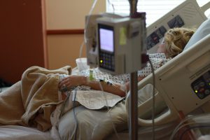 Caucasian woman sitting in a hospital room hooked up to an IV.