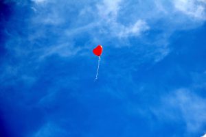 Red heart balloon floating in a blue sky. long-distance