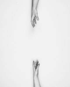 Two caucasian hands trying to reach each other to grab onto.