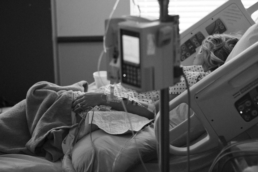 Black and white picture of a woman in hospital bed with IV