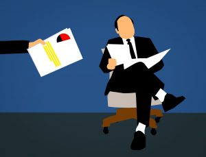 Cartoon of a man in a suit sitting on a chair with papers in his hand, with another hand in the picture giving paperwork to man sitting down.