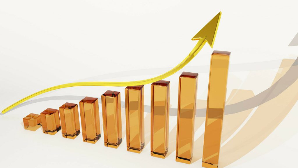 A graph of gold bars going up with an upward arrow above the bars.