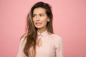 woman in pink making a face about menopause