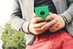 person with red pants emailing from their phone