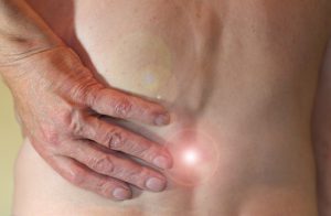 person's hand holding their lower back