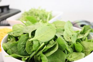 Bowl of spinach on a table.