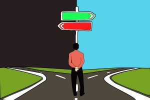Man standing at a crossroad with a green arrow pointing right to blue sky and red arrow pointing left to a black sky