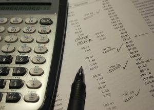 calculator and pen on top of a sheet with numbers on it.