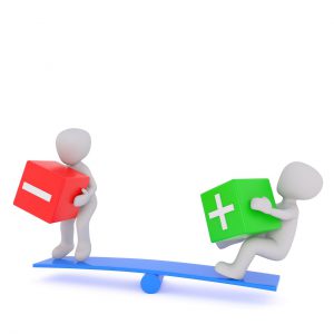 balance with two cartoons, on one side one holding a negative block and the other holding a positive block.