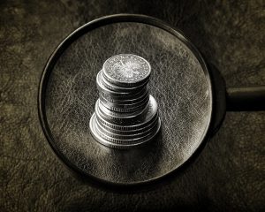 magnifying glass over a stack of coins.