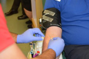 caucasian mans arm getting prepped by a medical professional with gloves on to get a needle put in.