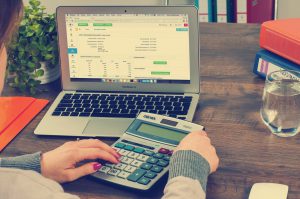 womans hands with calculator sitting in front of an open laptop
