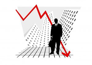 silhouette of a business man in suit and suitcase with a red line driving downwards behind him.