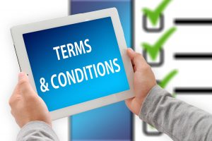 person holding a tablet with the words "terms & conditions" on it.