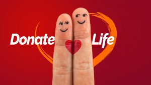 two fingers nect to each other with a heart connecting them with the words "donate life" around them.
